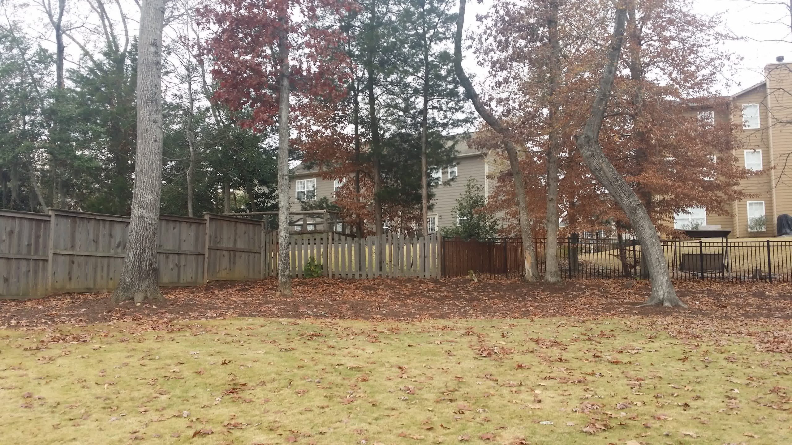 solomons yard cleanups fountain inn sc scaled - Solomon's Landscape & Design Front porch flower bed with mulch, small evergreen bushes, a welcome flag, and a young tree centered under large front windows.